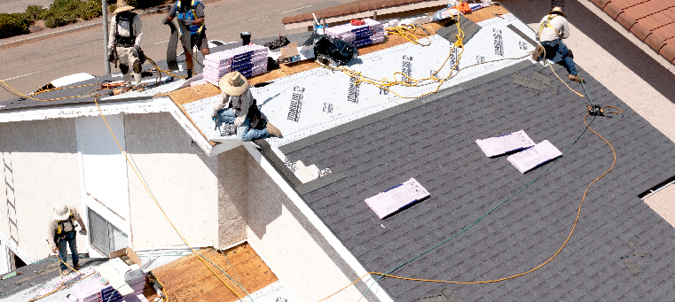 Five solar-panel installers replacing old shingles on a single family home.