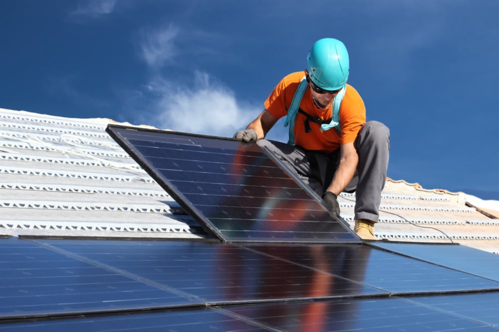 Worker installs solar panels on rooftop