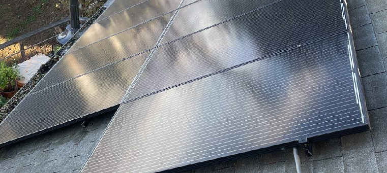 Solar panels on gray, asphalt-shingle roof of single-family home.